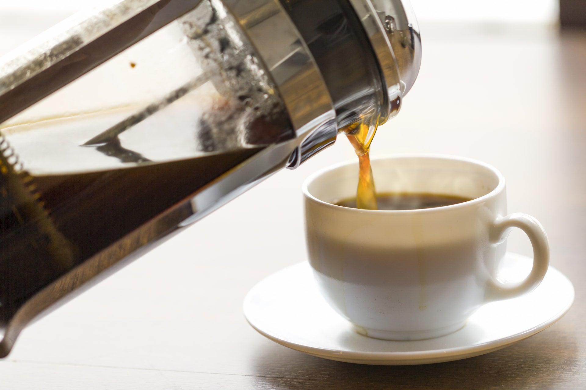 A fresh cup of coffee poured from a French Press