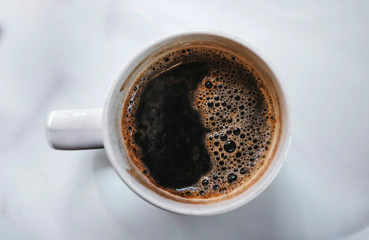 A mug full of dark black coffee on a white counter