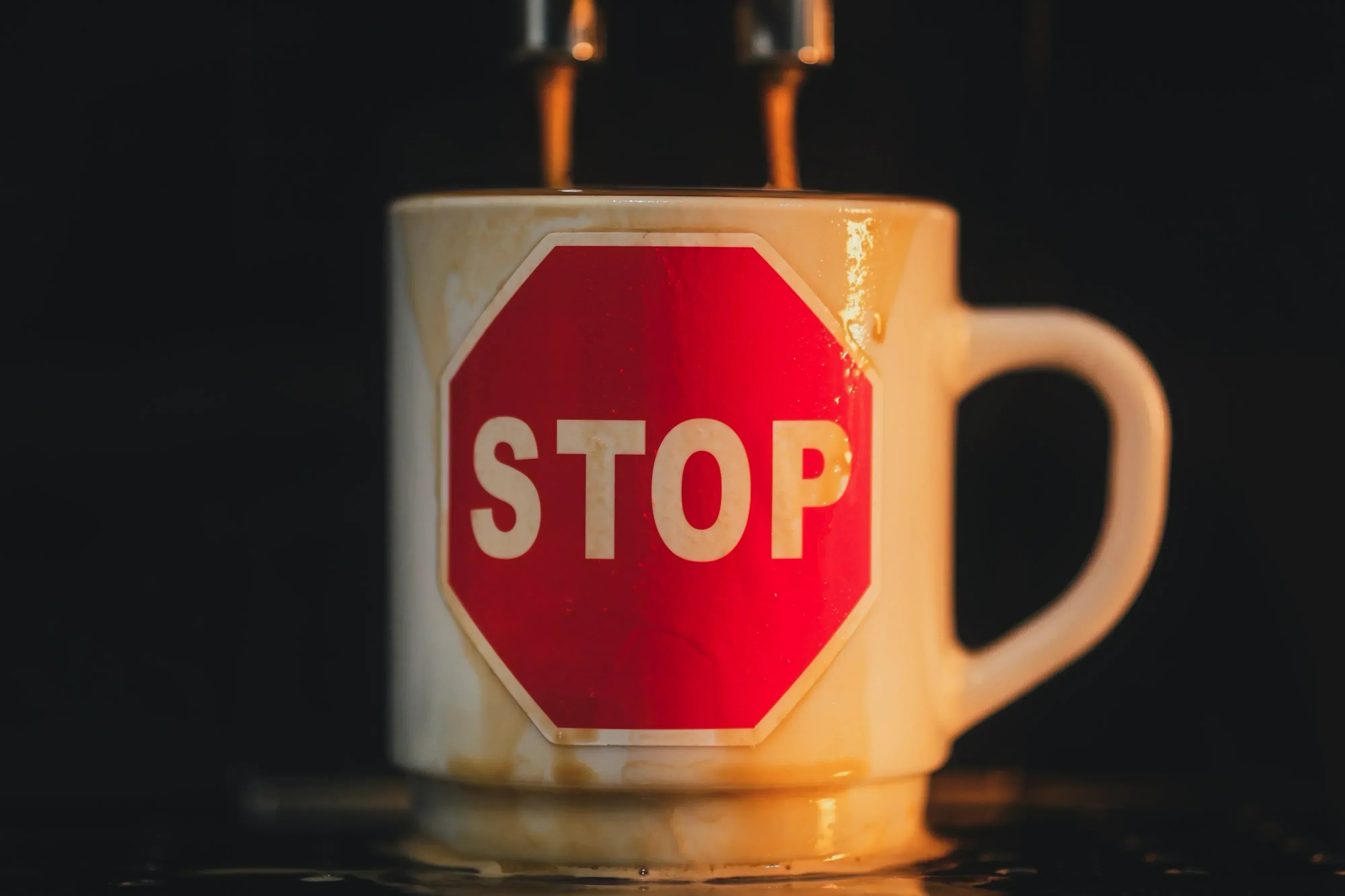 An overflowing cup of coffee with a red STOP sign printed on it.