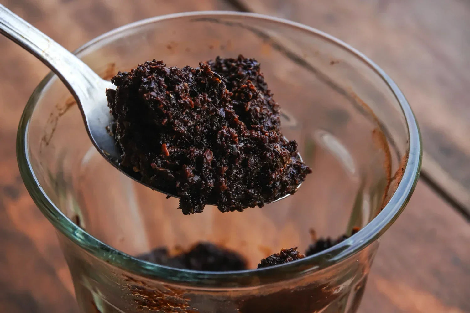 Used Coffee Grounds in a spoon and glass cup.