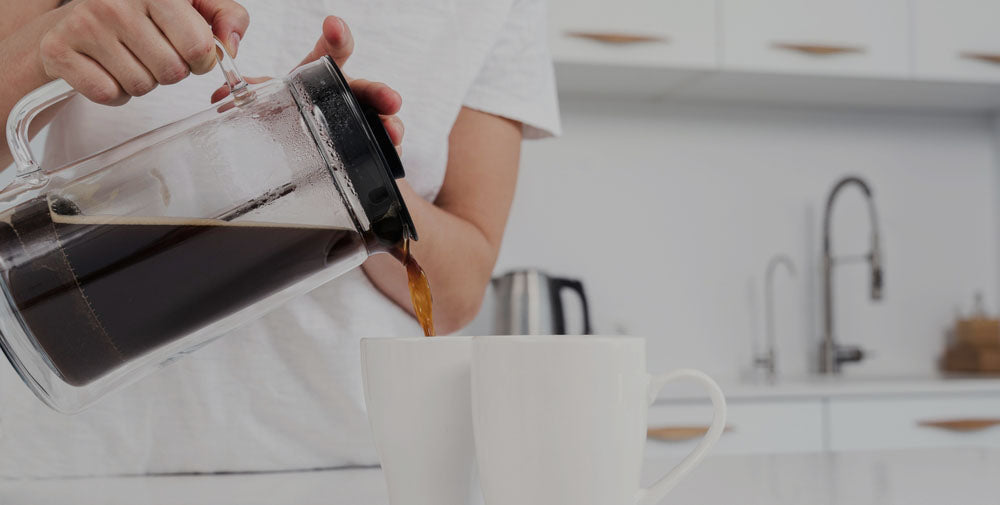 A woman pouring French press coffee into white coffee cups