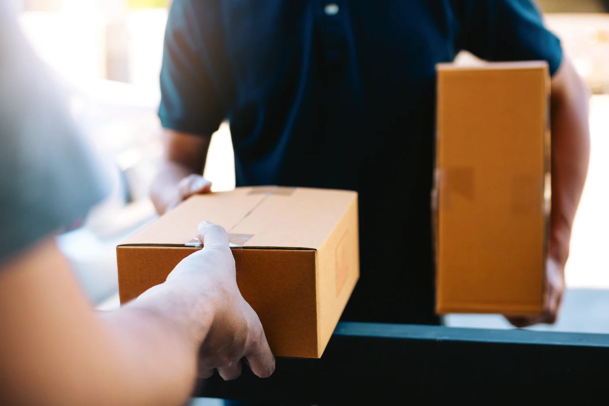 A delivery person bringing a monthly coffee subscription order to a customer's door and handing it to them.