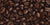 Glossy brown coffee beans are piled closely together, showcasing their textured surfaces and distinctive central grooves, filling the entire frame.