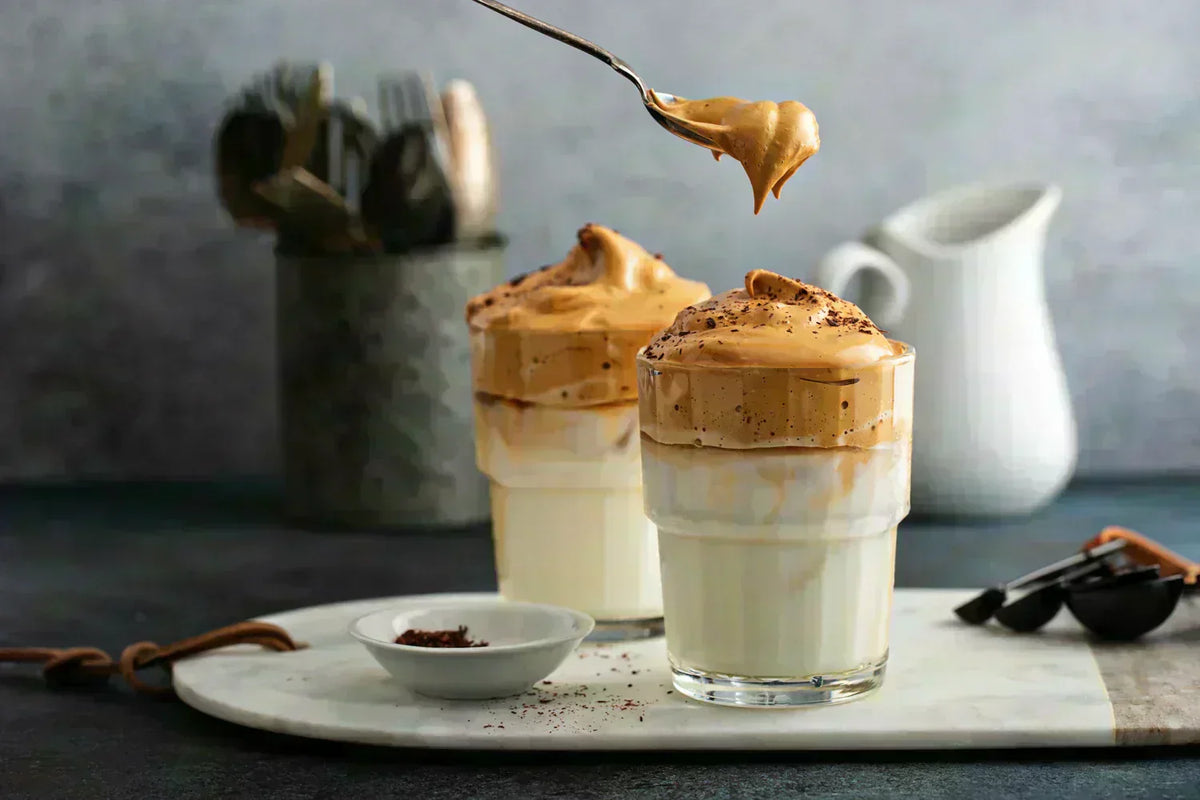 Someone spooning whipped coffee onto milk