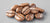 Coffee beans are scattered and resting on a smooth, light gray surface. The beans are shiny, with visible natural grooves and variations in texture.