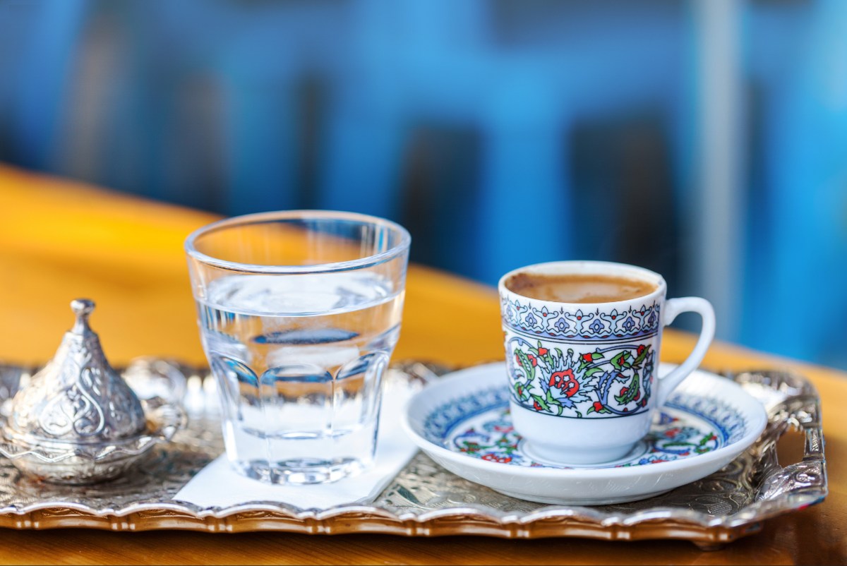 A tray with a cup of Turkish coffee and a glass of water. 