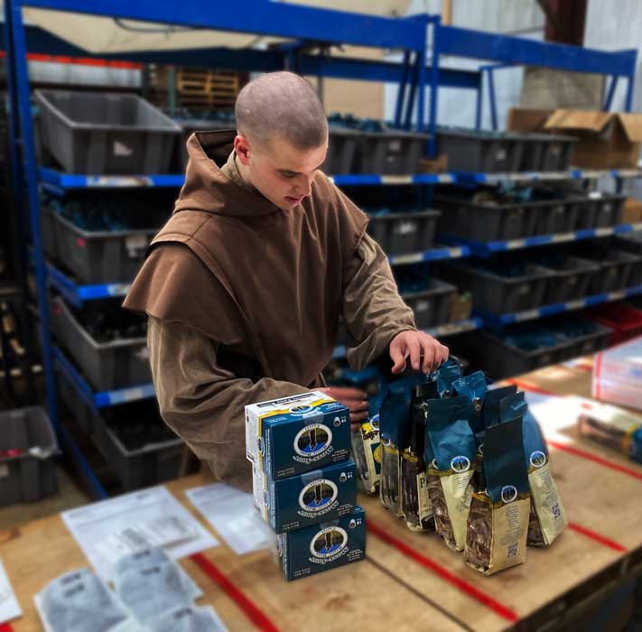 A Carmelite Monk and coffee artisan preparing orders of Mystic Monk Coffee to be sent out to monthly coffee subscription customers.